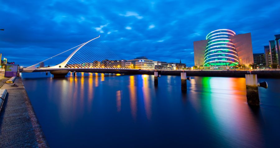 Image of the samuel beckett bridge at night and the convention centre in Dublin lit up with Ireland's national colours